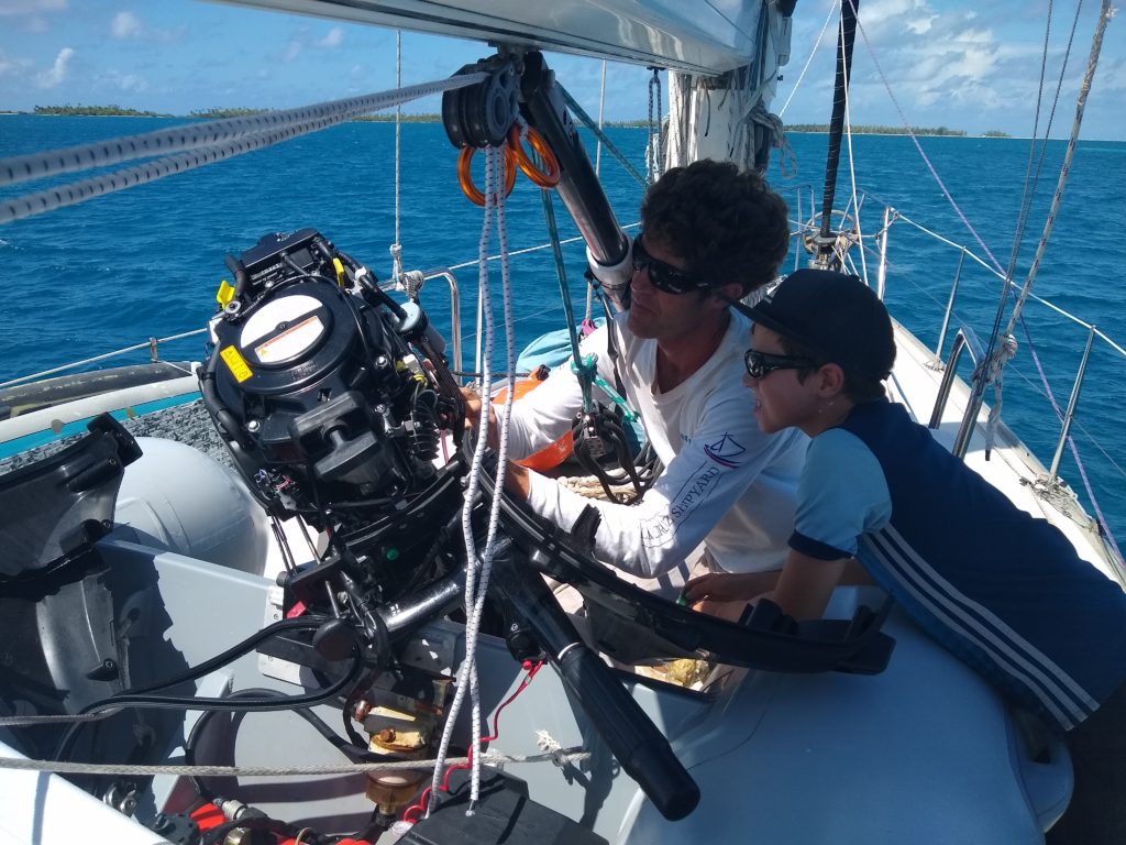 Nathan and Gavin doing an oil change on our outboard while we motor sail the 26 miles inside of Fakarava to the Harifa anchorage.
