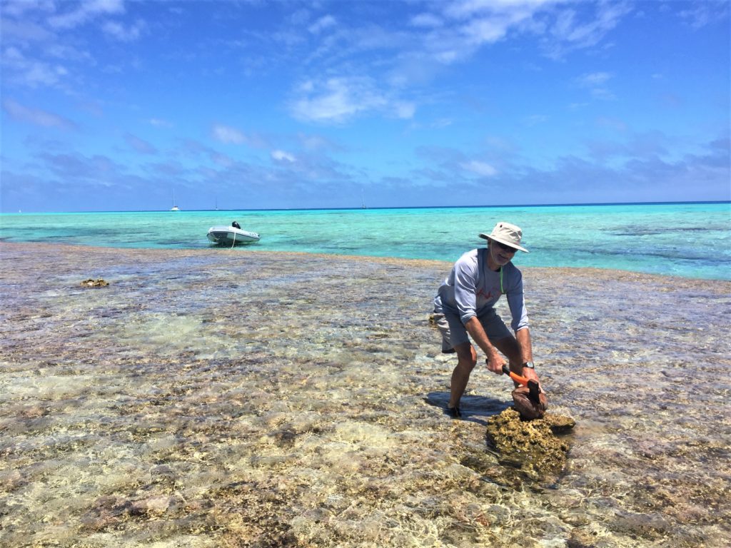 Finding a rock to chop open one of the coconuts we brought with us.